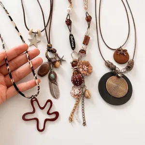 Bohemian necklaces with vintage feathers, wooden beads, and turquoise elements on white background