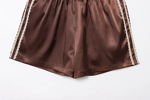 Detailed view of brown satin shorts featuring delicate white lace side trim decoration