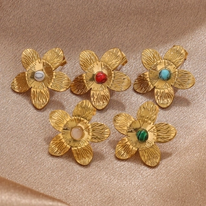 Detail of five-petal gold earrings featuring brushed metal and inlaid gemstones