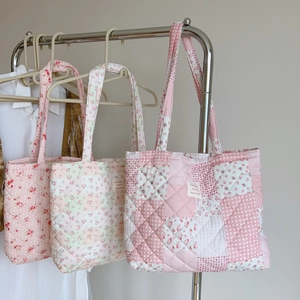 Quilted floral patchwork cotton tote bag hanging on a rack in a minimalist setting