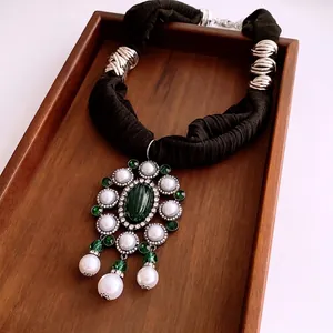 Vintage necklace featuring emerald gemstone and white pearl pendants on black fabric cord