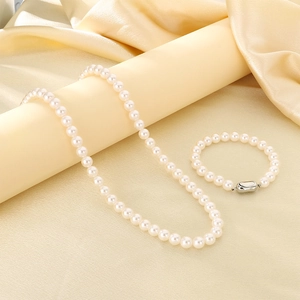 Détail d'un ensemble élégant de collier et bracelet en perles de verre blanches et argent