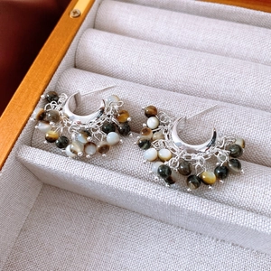 Detail of beaded tassel earrings with silver C-hoops on grey velvet jewelry box