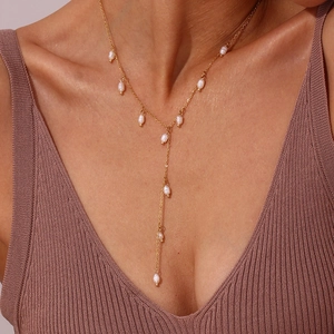 Détail d'un collier en Y doré avec perles d'eau douce sur un mannequin femme