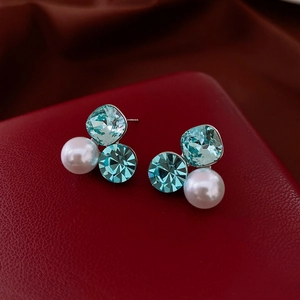 Macro shot of silver flower earrings with blue crystals and a white round pearl