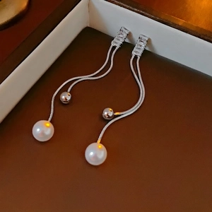 Silver fringe tassel earrings with zircon studs and white pearls on jewelry box