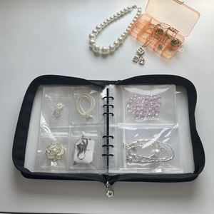 Macro detail of jewelry organizer book showing PVC pockets with earrings and necklaces