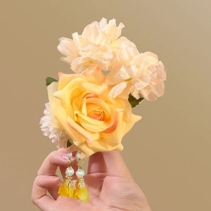 Detailed close-up of yellow silk rose hair clip with elegant tassels and pearls