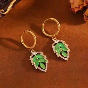 Elegant leaf-shaped earrings with green opal and diamonds on a vintage brown background