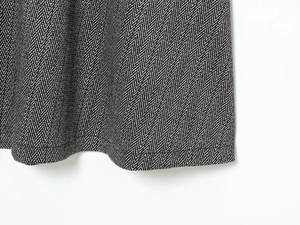Détail macro du tissu sergé et de l'ourlet piqué sur une robe à chevrons noir et blanc