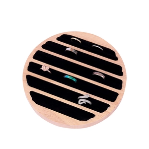 Detail shot of a round wood ring display tray with 6 rings in black velvet slots