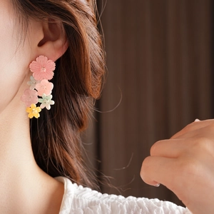 Macro detail of colorful resin flower tassel earrings worn by a model for beach style