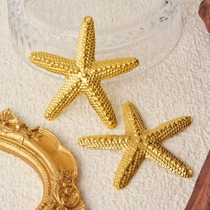 Golden 304 stainless steel starfish pendants with hammered texture on beige fabric