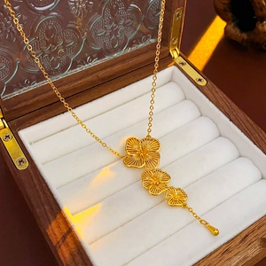 Detailed view of a gold-plated flower tassel necklace in a premium wooden jewelry box