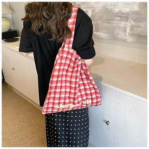 Detail of a large pink and white checkered tote bag with sleep well text embroidery
