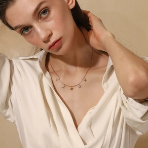 Detail of 18K gold-plated necklace with colorful starfish pendants worn by a model