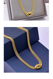 Macro shot of gold Evil Eye necklace with deep blue crystal on woven flat chain