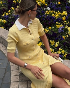 Detail view of the yellow knit dress with white contrast collar and metal buttons