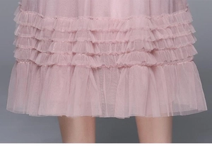 Gros plan détaillé de l'ourlet à volants en maille rose multicouche de la robe