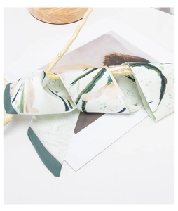 Close-up of long floral silk scarf wrapped around a wooden branch for styling