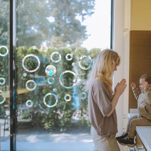 Rainbow prism window film with circular bubble patterns on glass in a family setting