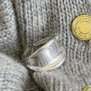 Close-up of a wide polished 925 sterling silver open ring on gray knit background