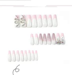 Close-up of pink French press-on nails with silver snake charm and glitter details