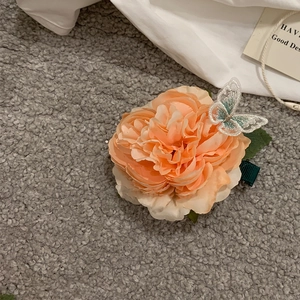 Close-up of peach fabric flower hair claw with an embroidered lace butterfly detail