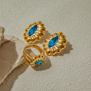 Detail of vintage gold ring and earrings set with blue oval gemstones on stone background