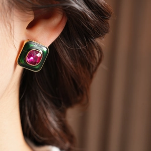 Close-up of vintage square stud earring with green enamel and rose red gemstone inlay