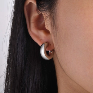 Close-up of woman wearing a minimalist silver wide hoop earring in polished finish