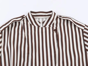 Detail of striped shirt featuring buttoned epaulettes and vertical brown black stripes