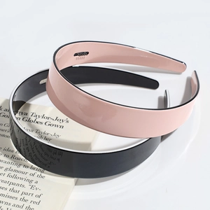Two wide non-slip hairbands in black and pink, displayed on a stylish book page background