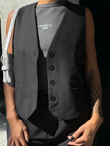 Detail of black single-breasted vest over a grey rib-knit tank top with Tribeca print