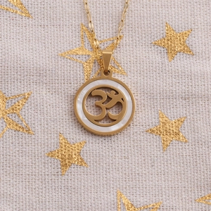 Macro shot of gold Om symbol pendant necklace with white shell inlay on star fabric