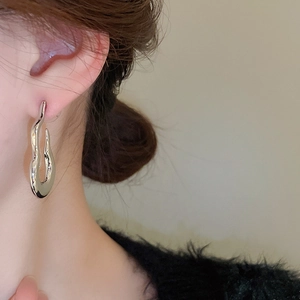 Macro shot of a silver flame gourd earring with polished liquid metal texture