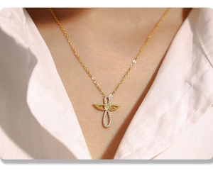Gros plan d'un collier doré multicouche avec pendentif ailes d'ange et croix en zircon