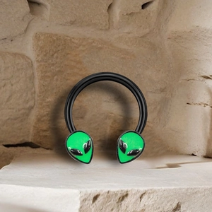 Alien head horseshoe nose ring in black metal finish on a textured stone background