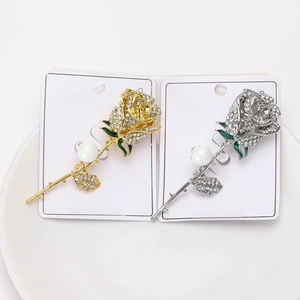 Macro detail of rose flower brooch with rhinestones and pearl on white card