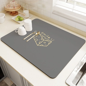Detail of grey absorbent kitchen mat featuring Smile text and cheese pattern on counter
