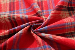 Macro shot of red and green plaid fabric texture with woven cotton tassels