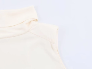 Close-up of the elegant high-neck collar and detailed shoulder stitching on a cream top