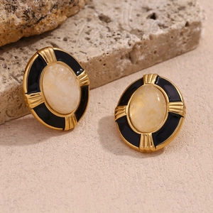 Detail of 18K gold plated oval earrings with natural stone on a neutral stone background