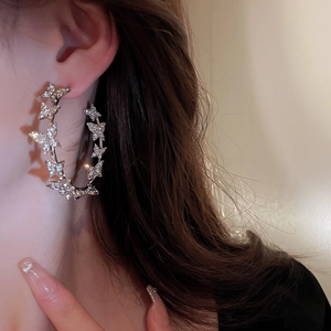 Close-up of sparkling butterfly hoop earrings featuring micro-pave crystals on model