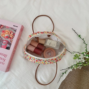 Detail of floral zipper pouch showing leather handle and cosmetic storage space
