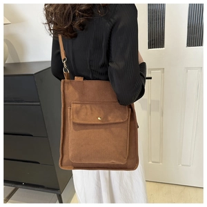 Detail showing brown corduroy tote bag with metal buckle and large front pocket