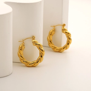 Detailed view of the 18K gold-plated chunky C-shape hoop earring on a white stone pedestal