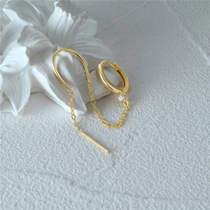 Detail of gold chain earring with sparkling zircon clover dangle and polished hoop