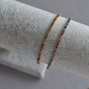 Detail view of gold and silver bracelets featuring colorful candy-like gemstones