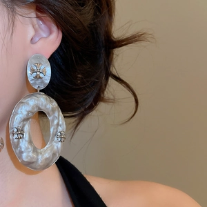 Detail of acrylic marble drop earrings featuring vintage metal gothic cross elements